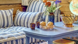 Un cuarto acogedor con asientos tapizados a rayas, una pequeña mesa con objetos decorativos, incluyendo un florero con flores, un globo terráqueo y una jarrilla.