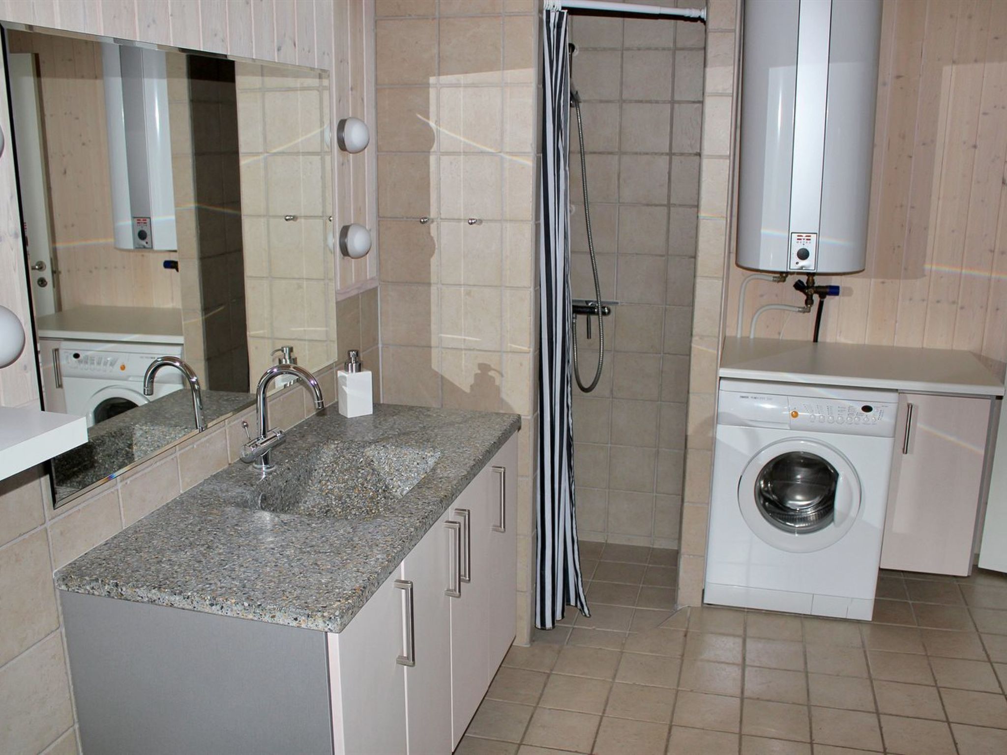 A compact laundry room with a washing machine, a sink, and a shower.