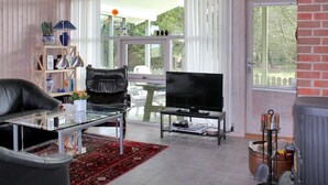 A modern living room with a glass coffee table, leather sofa, and a flat-screen TV.