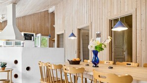 Ett modernt kök med väggar beklädda med träpaneler, ett långt matbord och blå hänglampor.