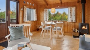 A cozy cabin interior with wooden walls, a dining area, a sofa, and a wood-burning stove. - "Asmo" - 350m from the sea by Interhome (Fjerritslev)