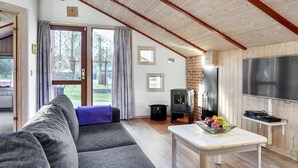 Een gezellige woonkamer met een bank, een tafel met fruit, een televisie en een open haard.