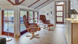 Een ruime kamer met hoge plafonds, grote ramen en een houten vloer. Er staan twee leren fauteuils en een klein tafeltje.