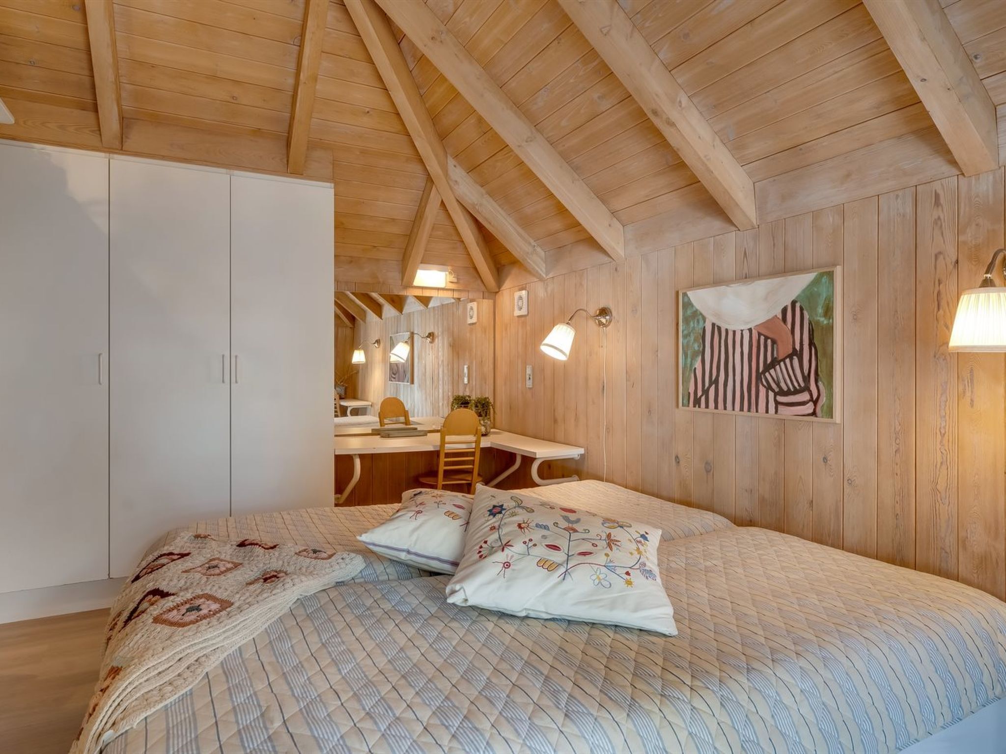 L'intérieur d'une cabane en bois, avec un lit, un bureau et une chaise.