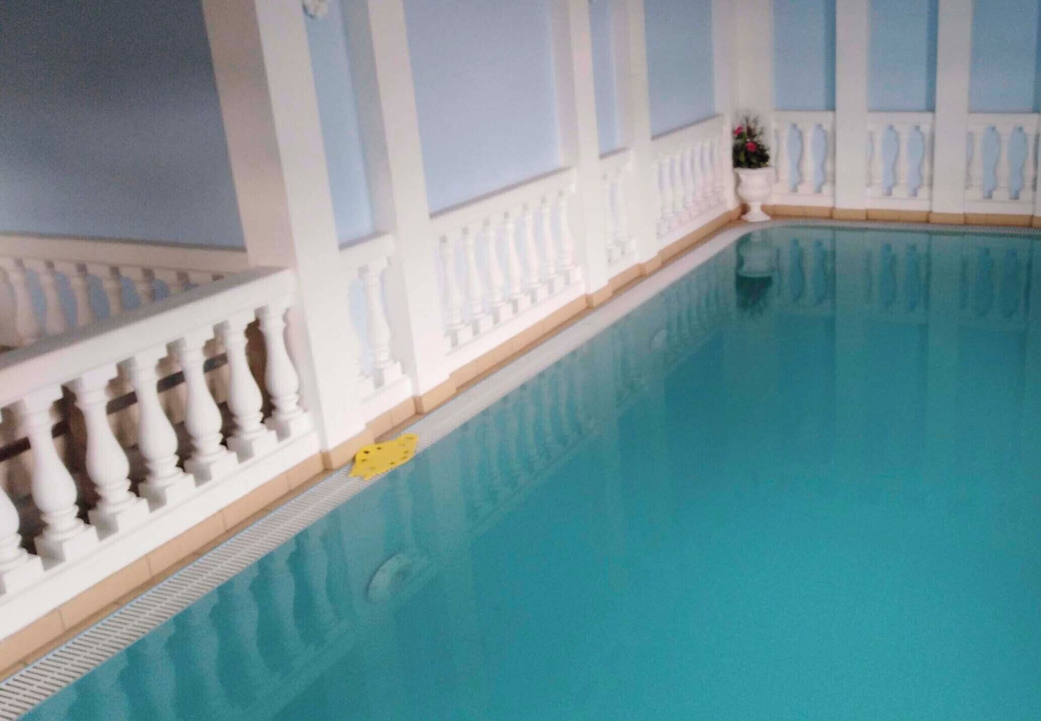 An indoor swimming pool with white balustrades and a yellow lifeguard float.