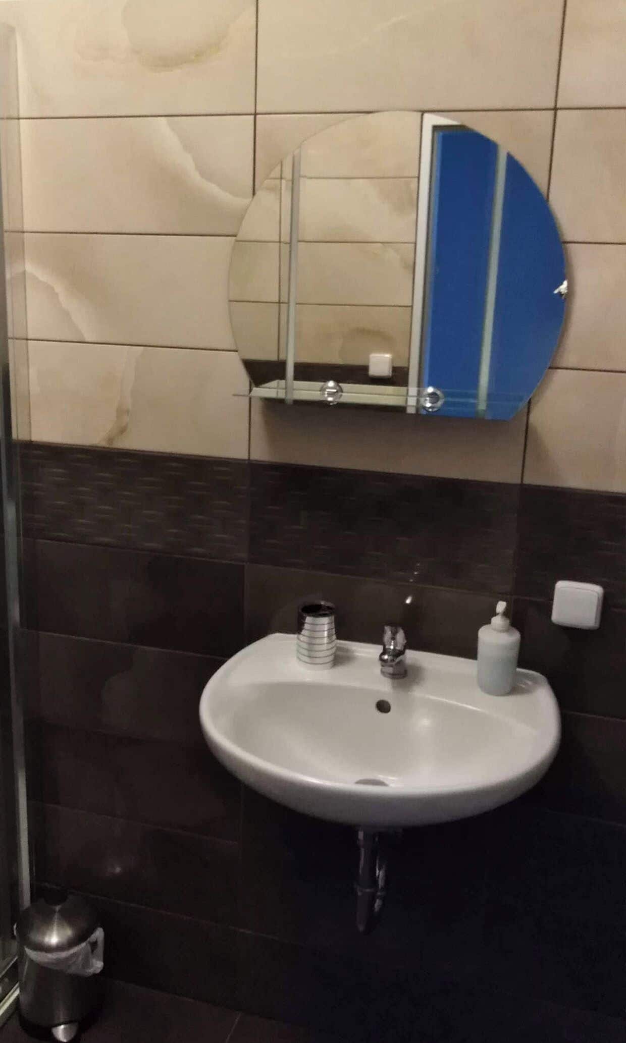 A bathroom with a white sink, a mirror, and a blue-framed mirror.