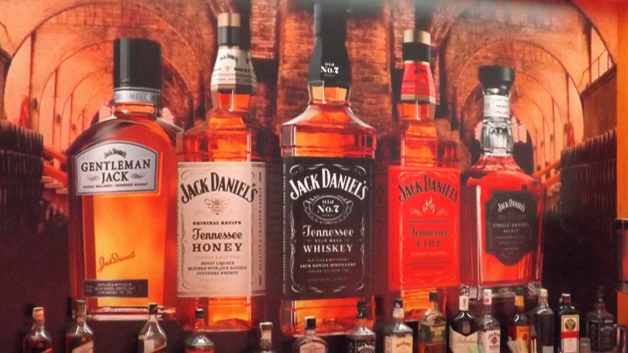 Forskellige flasker af Jack Daniel's whiskey står fremstillet på hylder.