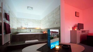 A modern bathroom with a bathtub, a towel rack, and a table with a candle. - Hotel Styria (Chvalovice)