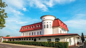 A white building with a red roof and a round tower, labeled "HOTEL". - Hotel Styria (Chvalovice)