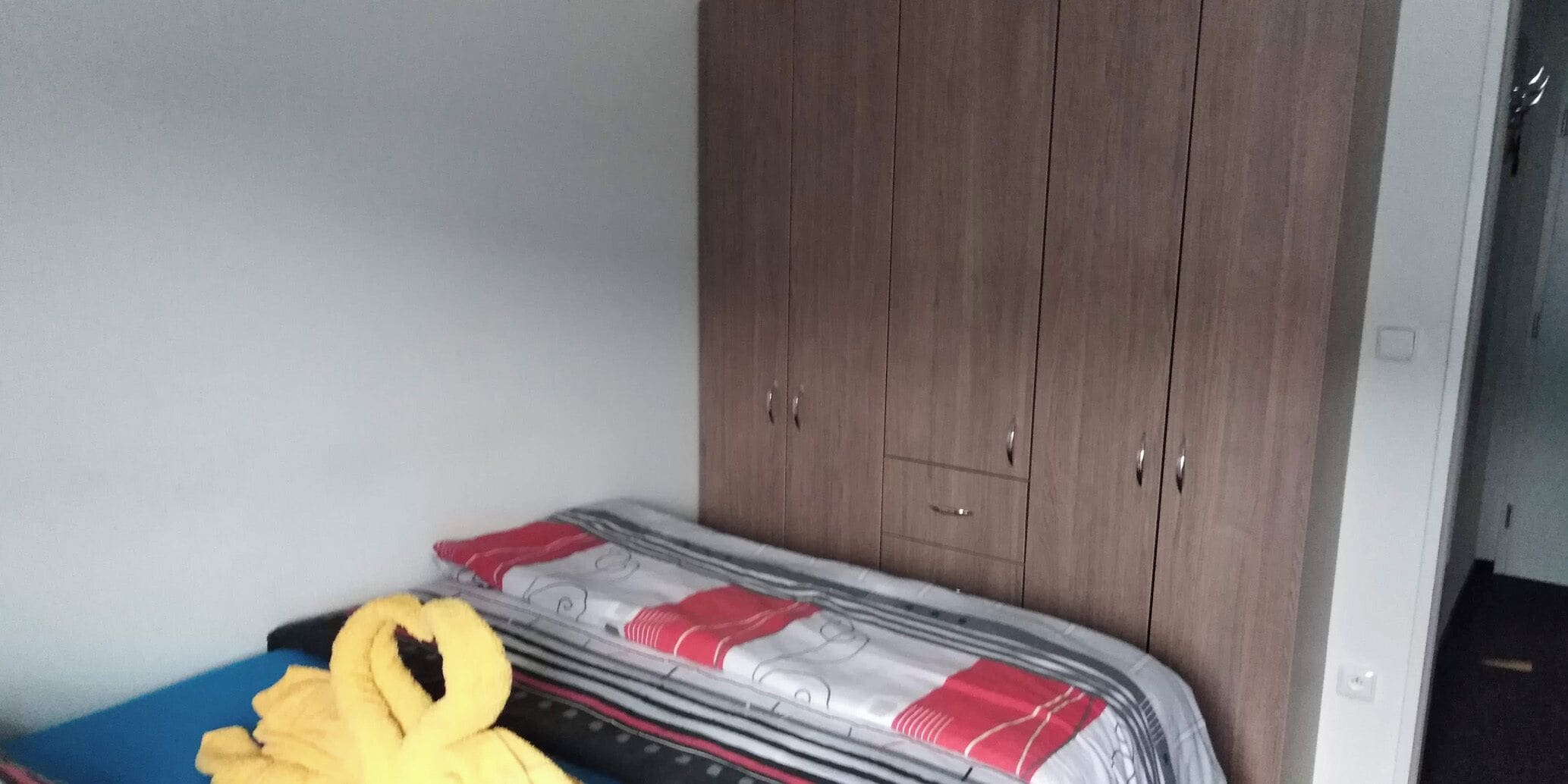 Un dormitorio con una cama, un armario y un objeto amarillo sobre la cama.