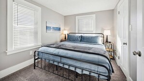 Een slaapkamer met een bed, twee nachtkastjes en een deur.