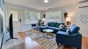 A modern living room with a sectional sofa, a small side table, and a television on a stand.
