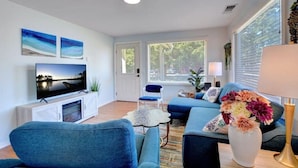 A modern living room with a flat-screen TV, blue sofas, and a decorative vase.