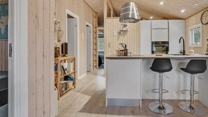 Une cuisine moderne dotée d’un îlot central, de tabourets de bar et d’un luminaire suspendu.