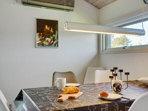 Ein Essbereich mit Tisch für zwei Personen, ausgestattet mit einer schwarzen Tischdecke mit weißen Kritzeleien, einem Croissant, einem Muffin, einer Tasse und einer Kaffeetasse.