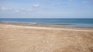 Una playa con cielo despejado y mar tranquilo.