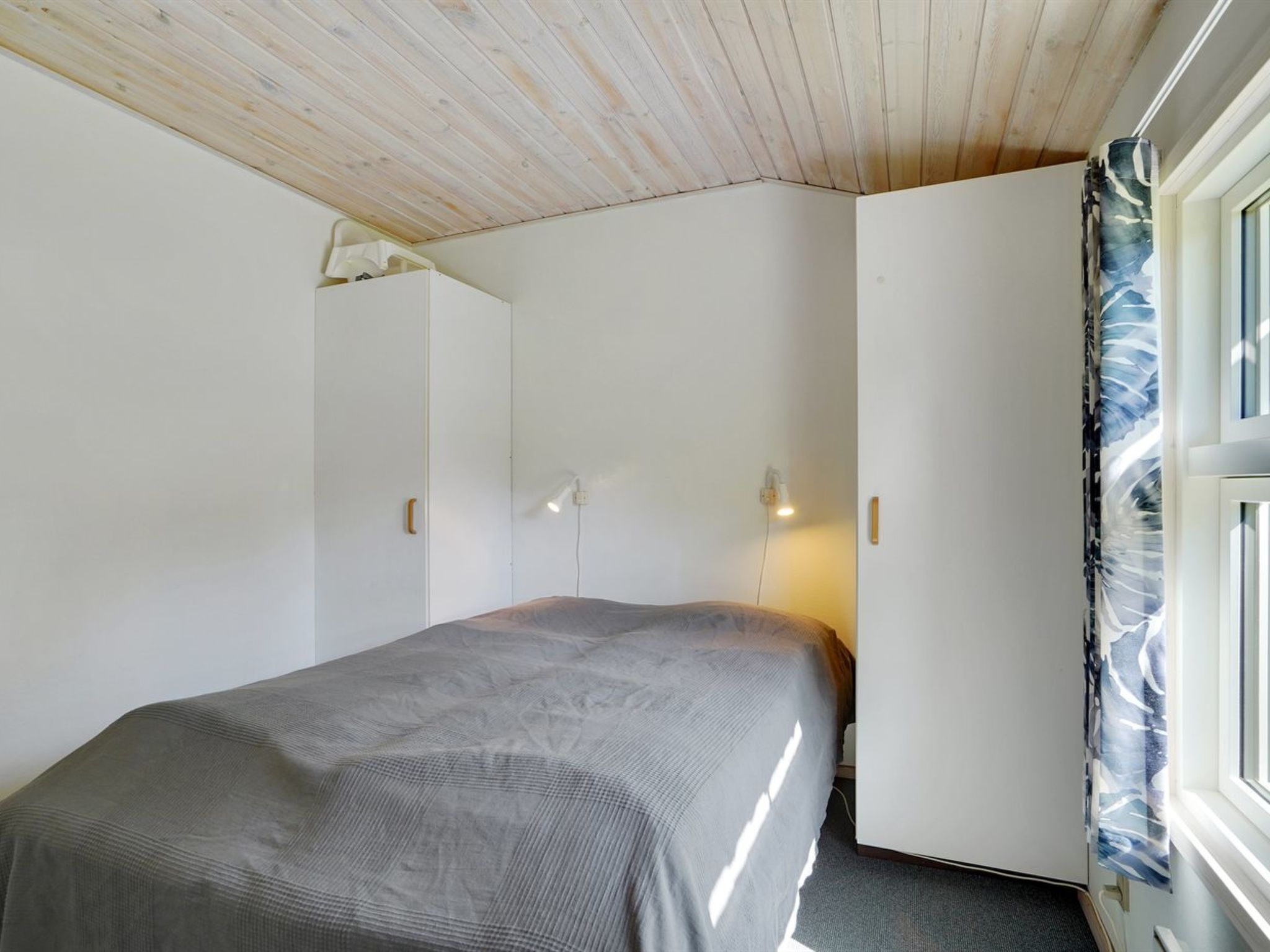 Ein Schlafzimmer mit einem Bett, einem Kleiderschrank und einem Fenster mit Vorhängen.