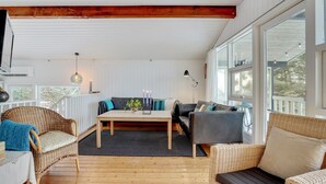 Ein gemütliches Zimmer mit Holzboden, einer Couch, einem Sessel und einem Tisch.