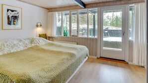 Ein Schlafzimmer mit einem großen Bett, Holzboden und Blick durch eine Schiebetür.
