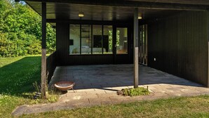 A modern building with a covered patio area, large windows, and a stone pathway.
