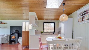 A cozy kitchen with a wood stove, white cabinets, and a dining area with a table and chairs.