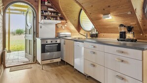 Eine kompakte Küche mit Herd, Backofen, Geschirrspüler und Kaffeemaschine.