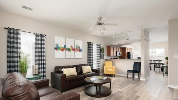 A modern living room with a sofa, coffee table, and chairs. There is a kitchen area in the background.