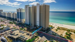 Un hotel costero con varias torres, un estacionamiento y vista a la playa.