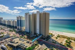 A coastal hotel with multiple high-rise buildings, a parking area, and a beach view.