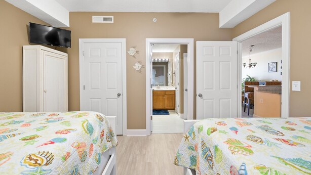 Un dormitorio con dos camas, televisión y un baño visible a través de una puerta abierta.