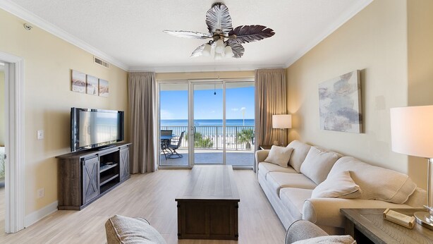 Ein Hotelzimmer mit Balkon, Fernseher, Sofa, Couchtisch und Deckenventilator.