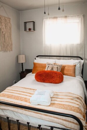 Cozy retreat with a bed, nightstand, and lamp, set against a wall with a geometric pattern above.