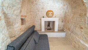 A cozy room with a stone wall, a fireplace, and a grey sofa. - 2 Bedroom Private vacation home in Monopoli (Monopoli)
