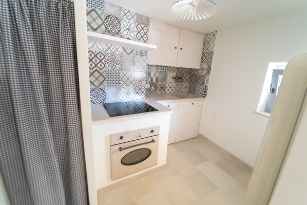 Une cuisine de taille réduite, avec des carreaux décoratifs, un four encastré et une fenêtre.