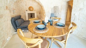 A dining area with a round wooden table, six chairs, and a stone wall backdrop. - 2 Bedroom Private vacation home in Monopoli (Monopoli)