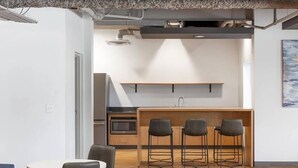 A modern kitchen with a central island, bar stools, and a microwave. - SLC - U of U - Hospital - Convention - Gym - Dining (Salt Lake City)