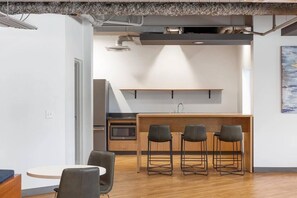 A modern kitchen with a central island, bar stools, and a microwave.