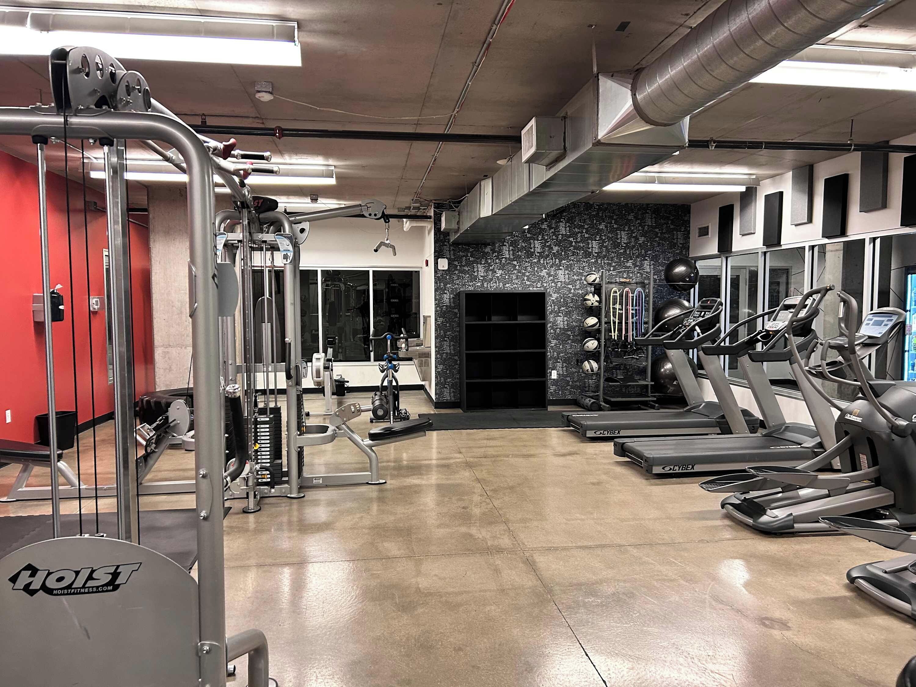 Un gimnasio con equipo de ejercicio, cintas de correr y un espejo grande.