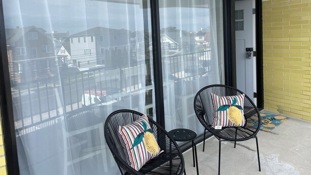 A balcony with two black wicker chairs, each with a striped pillow. - Settle In the Sun!
Fantastic centrally located North Wildwood Condo  (North Wildwood)
