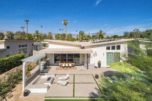 A modern house with a patio, outdoor seating, and a swimming pool.