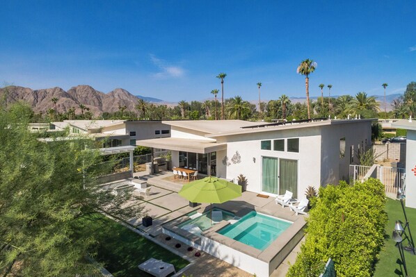 A modern house with a swimming pool, patio, and mountain views.