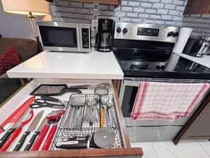 A kitchen with a microwave, coffee maker, stove, and various utensils. - Modern Cozy Luxury Suite in Ajax | 5 Min to Hwy 401 | Kitchen/ Laundry/Parking  (Ajax)