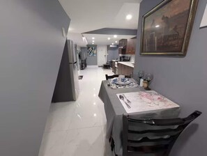 A modern kitchen with a dining area, featuring a table set for two with a vase of flowers. - Modern Cozy Luxury Suite in Ajax | 5 Min to Hwy 401 | Kitchen/ Laundry/Parking  (Ajax)