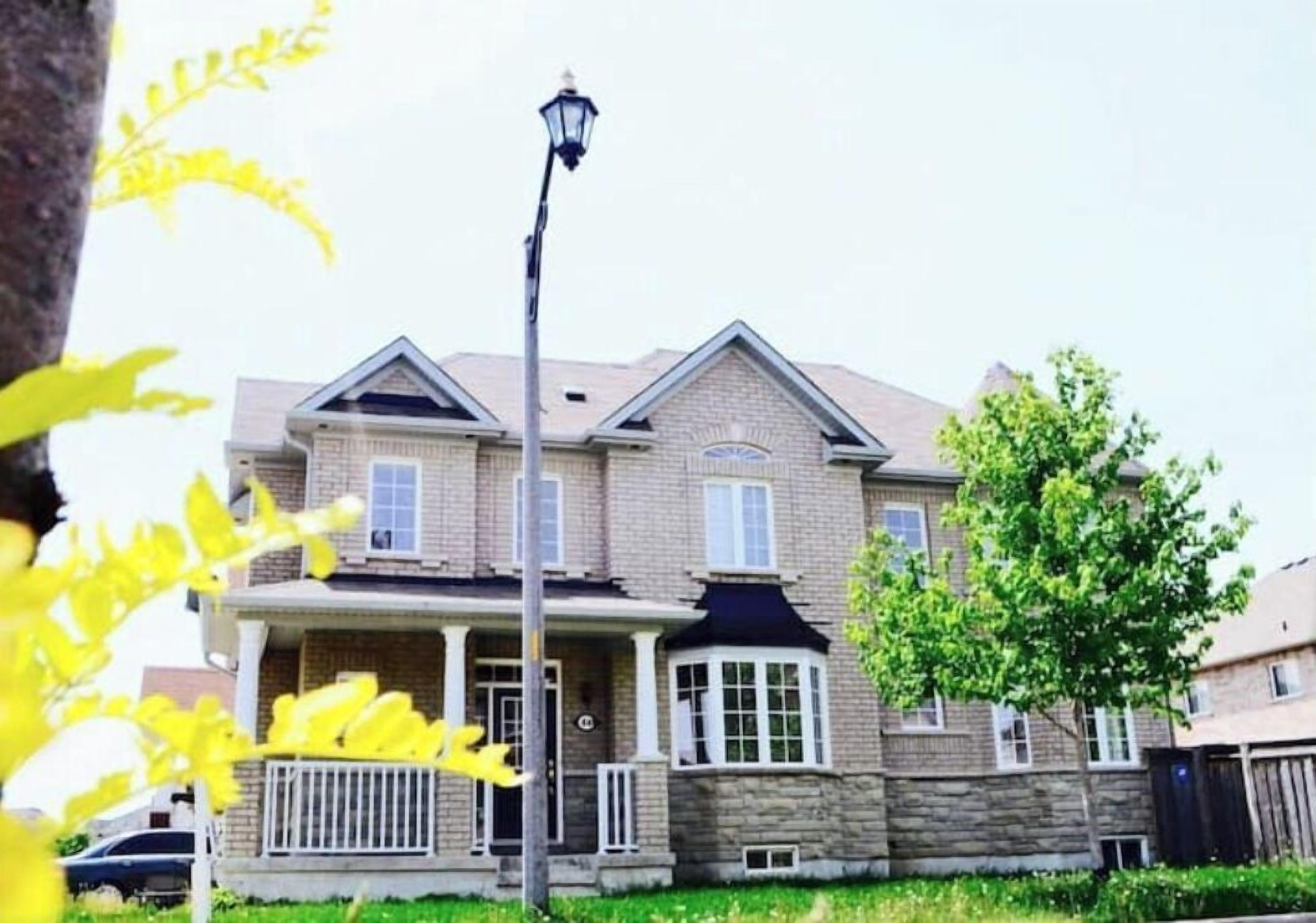 Une maison à deux étages avec une façade en pierre, un porche à l’avant et un lampadaire.