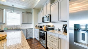 A modern kitchen with white cabinets, stainless steel appliances, and a granite countertop. - Resort Perks: Waterfront Rockport Home! (Rockport)