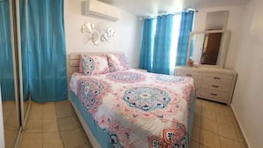Un dormitorio con cama, cómoda, espejo y aire acondicionado instalado en la pared.