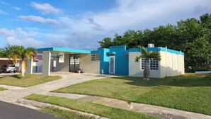Un edificio de dos pisos con fachada azul y blanca, un camino de entrada cubierto y un césped bien cuidado.
