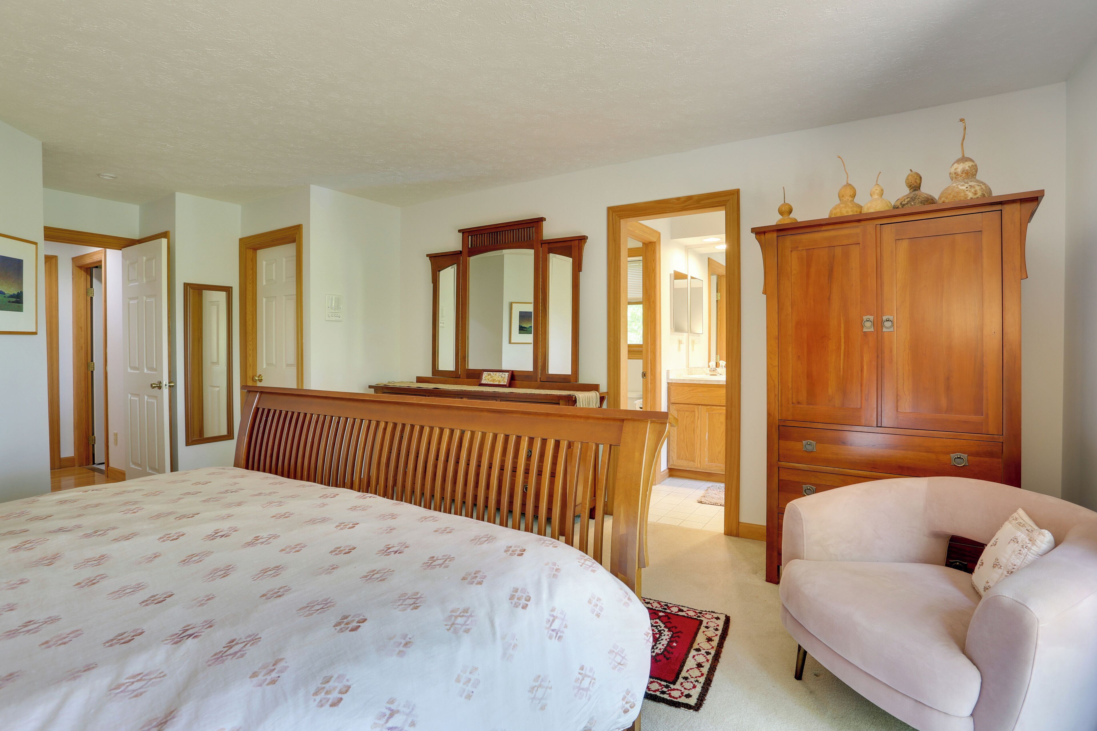 Un dormitorio con una cama, un aparador de madera, una silla y un espejo.