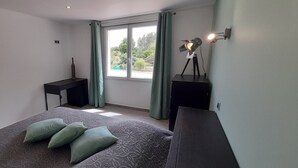 A bedroom with a bed, a desk, a lamp, and a window with curtains. - Sur les pas de Pagnol (Aubagne)