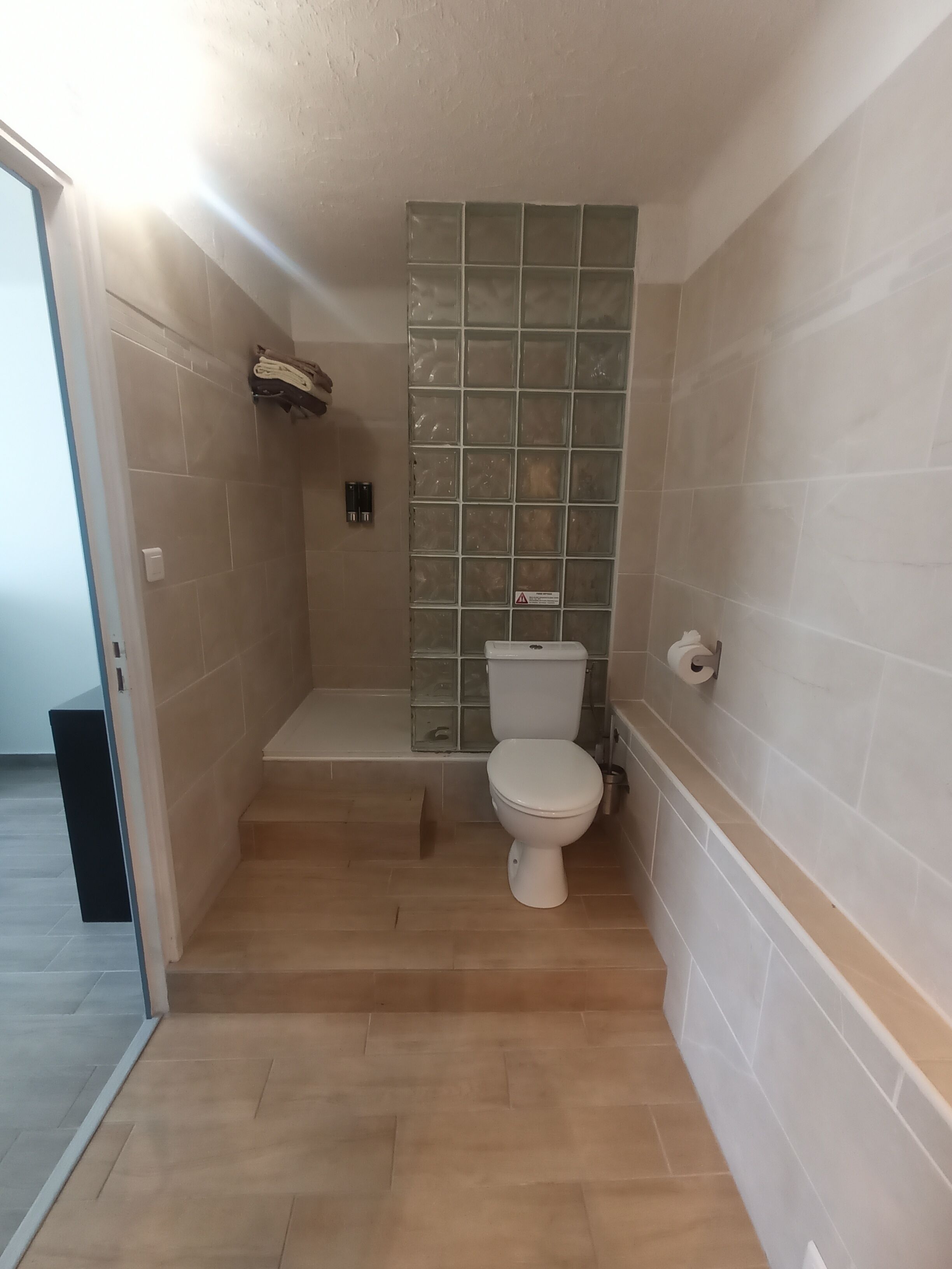 Une salle de bain équipée de toilettes, d’une douche et d’une paroi de séparation en verre.